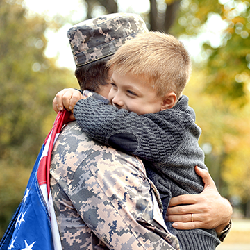 boy hugging his dad in uniform