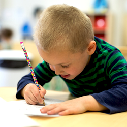 boy writing on paper with pencil 