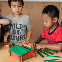 Boys playing with blocks building a house