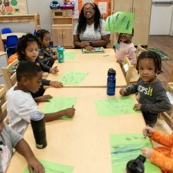 Children gathered around a table participating in a collaborative early learning activity.