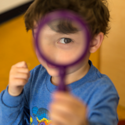 boy looking through purple magnifying glass