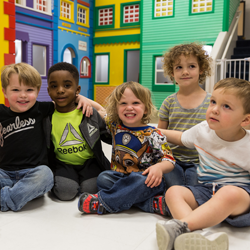 group of five kids smiling sitting on floor 