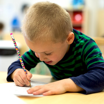 boy writing on paper with pencil 