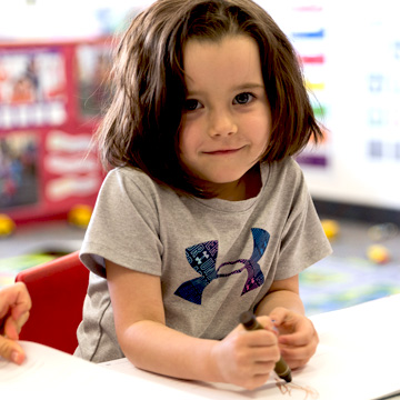 young kid drawing on paper with a crayon