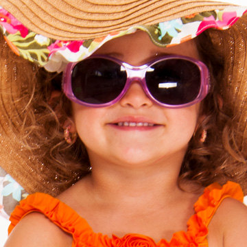 girl smiling in sunglasses and oversized hat