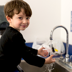 niño lavándose las manos en el fregadero sonriendo